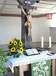 Kirchenaltar mit Jesukreuz, Sonnenblumen, Bibel und Kerzen